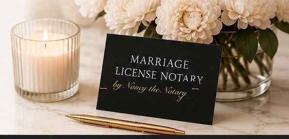 A lit ribbed candle, a black Marriage License Notary place card, and white flowers on a marble surface